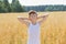 Teenage farmer standing among oat field
