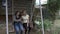 Teenage female friends taking a selfie with smartphone while they swinging outdoor relaxing together in the cradle -