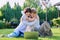 Teenage female student friends laughing sitting on grass with laptop