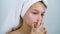Teenage girl with bath towel on head examining her face