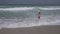 Teenage girl in a bathing suit happily jumps in waves of Persian Gulf on beach of Dubai