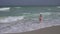 Teenage girl in a bathing suit happily jumps in waves of Persian Gulf on beach of Dubai
