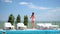 Teenage girl in bathing suit stands between sun loungers by pool background sea