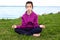 A teenage girl on the beach in the Lotus position jokingly Peeps with one eye