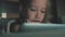 Teenage girl in bed playing a tablet in social internet in the dark light. Close up of little girl watching video on the