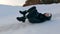 Teenage girl in black clothes slides down on back a slide at sunset in snowy winter forest. Winter fun and games