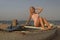 Teenage girl with blonde hair sit on an old boat to the shore of the sea