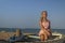 Teenage girl with blonde hair sit on an old boat to the shore of the sea