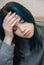 A teenage girl with blue hair is sad and depressed