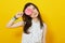 Teenage girl on bright vivid yellow background holding lollipop