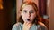 A teenage girl with brown hair and dyed bangs brushes her teeth before going to bed with a blue brush.