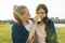 Teenage girl comforts her crying, upset, sad friend. The girls are sitting on the green grass in the park