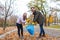 A teenage girl with a dad is cleaned in an park, collecting the fallen foliage in a garbage bag.