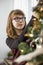 Teenage girl decorating Christmas tree at home