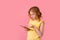 A teenage girl does her homework on a tablet. The student works and communicates with friends. Isolate on a pink background