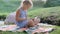 a teenage girl draws sitting on the nature near the river.