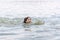 A teenage girl enjoys swimming in the calm warm lake water in beautiful summer weather