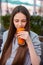 teenage girl enjoys and tastes fresh juice, drinking pumpkin smoothie outdoors