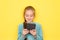 Teenage girl enthusiastically reads an e-book isolated on yellow background. Girl using tablet device, reading e book