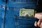 Teenage girl grabs dollar banknotes from her back pocket. Banknotes close up, money in a jeans pocket. Dollars stick out of the