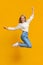 Teenage girl having fun jumping in air on orange background