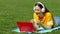 Teenage girl having a video call with a laptop on the grass