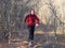 Teenage girl in headphones runs along a forest trail with a backpack