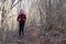 Teenage girl in headphones runs along a forest trail with a backpack