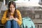 Teenage girl in headphones takes notes in a notebook, learns online sitting on the stairs in the park