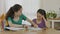 Teenage girl helping her young sister with homework during the COVID-19 pandemic