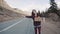 Teenage Girl Holding An Adventure Sign On A Mountain Road, Smiles And Laughs. Hitchhiking in search of adventure.