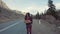 Teenage Girl Holding An Adventure Sign On A Mountain Road, Smiles And Laughs. Hitchhiking in search of adventure.