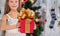 Teenage girl holding Christmas present in front of New Year tree