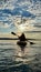 teenage girl is kayaking at sunset in Pacific Ocean, only the silhouette of Kayak Paddles is visible she swims along