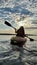 teenage girl is kayaking at sunset in Pacific Ocean, only the silhouette of Kayak Paddles is visible she swims along