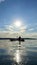 teenage girl is kayaking at sunset in Pacific Ocean, only the silhouette of Kayak Paddles is visible she swims along