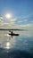 teenage girl is kayaking at sunset in Pacific Ocean, only the silhouette of Kayak Paddles is visible she swims along