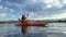 Teenage girl is kayaking at sunset in Pacific Ocean, only the silhouette of Kayak Paddles is visible she swims along