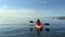 Teenage girl is kayaking at sunset in Pacific Ocean, only the silhouette of Kayak Paddles is visible she swims along