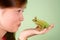 Teenage girl kissing Tree frog Litoria infrafrenata with a crown on his head