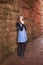 Teenage girl leaning against an old wall with her hands under he