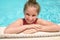 Teenage girl leaning on edge of swimming pool