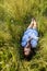 A teenage girl lies in a tall meadow grass