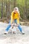 A teenage girl with long blond hair plays with a stick with a dog in the park.