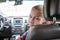 Teenage girl looking back from passenger front seat of car, Caucasian child