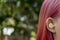 Teenage girl with ombre colored pink hair with wireless earbuds earphones in her ear. Music phone calls podcast audiobooks