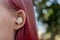 Teenage girl with ombre colored pink hair with wireless earbuds earphones in her ear. Music phone calls podcast audiobooks