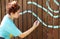 A teenage girl paints with a brush on a brown fence