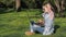 A teenage girl in a park with a laptop. Beautiful girl is sitting on the grass with a laptop. Spring sunny day in nature.