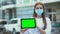 Teenage girl in protective mask holding green screen tablet, flu prevention tips